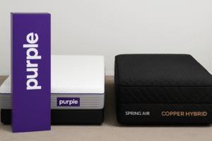 Purple mattress beside a Spring Air Copper Hybrid mattress with a black cover and copper stitching, shown side by side with a Purple box in a clean showroom setting.